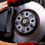 a person in red gloves is holding a brake disc